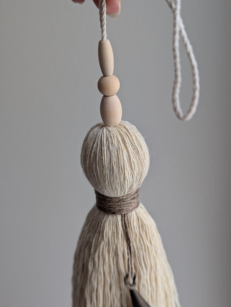 Decorative tassel with wooden beads on a gray background