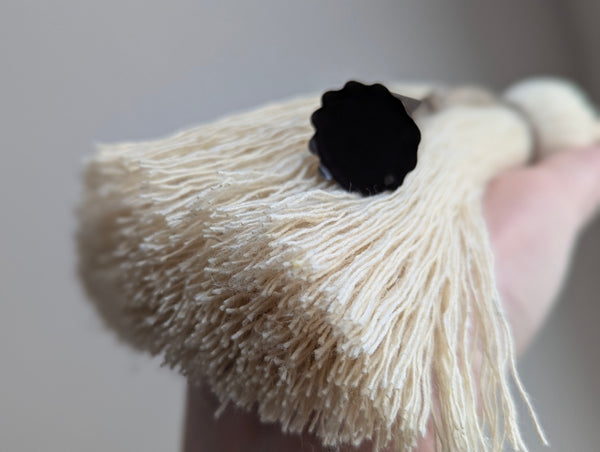 Close-up of a tassel with a dark brown bell against a neutral background