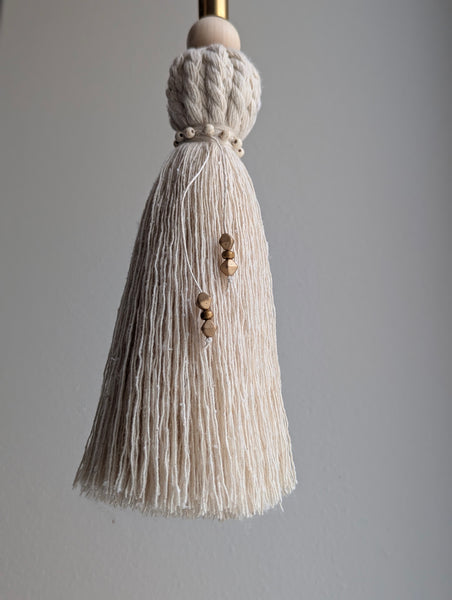 Beige tassel with wooden beads on a gray background