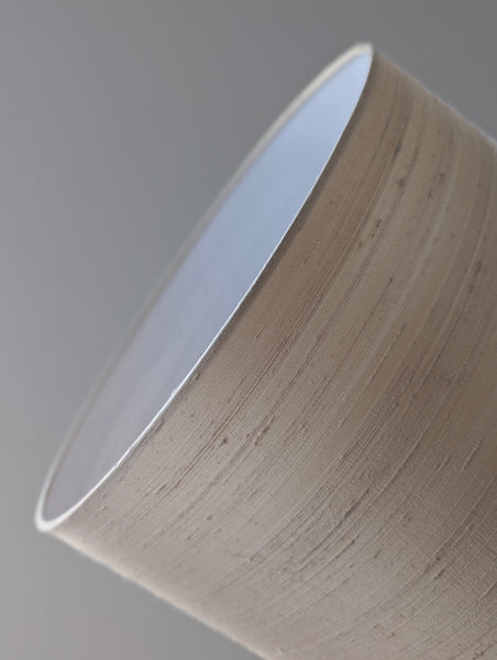 Close-up of a cream silk lampshade on a plain background