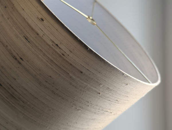 Close-up of a textured lampshade with brass spider hardware