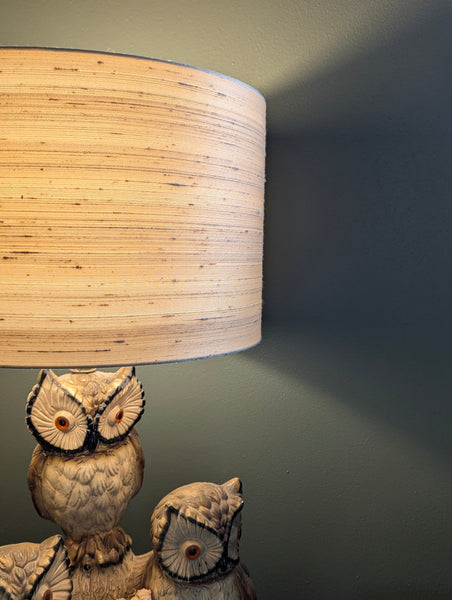 Lamp with silk shade and owl-shaped base against a dark green wall