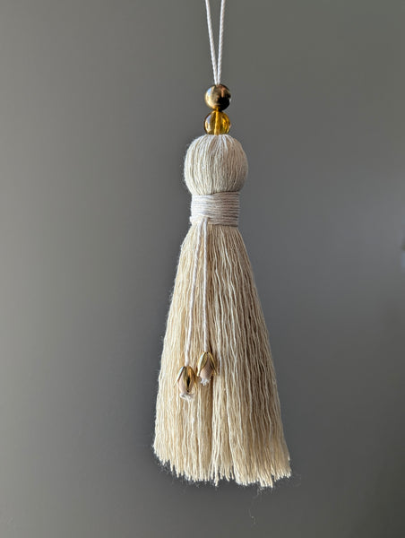 Decorative tassel with a gold bead on a gray background