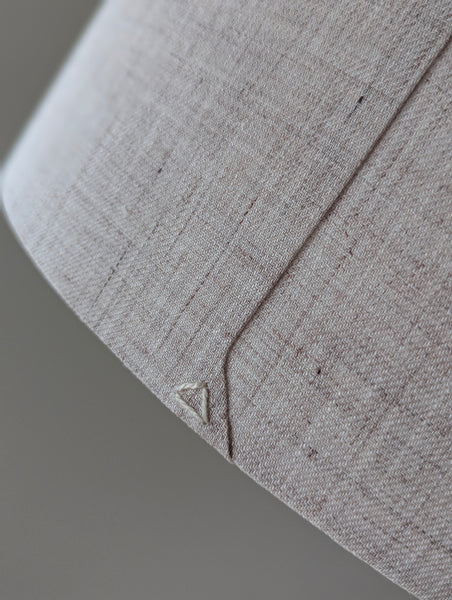 Close-up of a beige linen lamp shade with a triangle stitch detail on the back seam