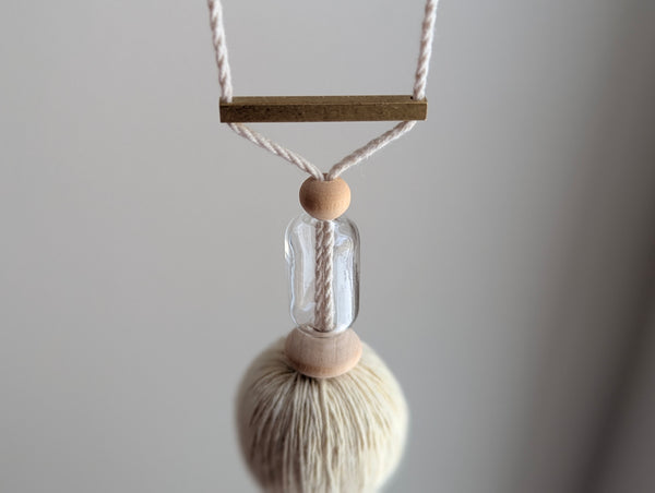 Decorative tassel with wooden and glass beads and a brass bar on a gray background