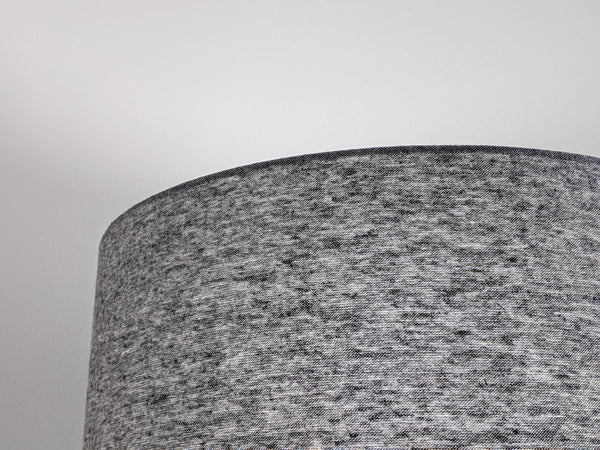 Close-up of a textured gray lampshade lit against a light gray background