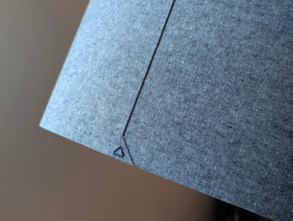 close up showing a black triangle stitch detail on the back seam of an oval lamp shade in black and white fabric