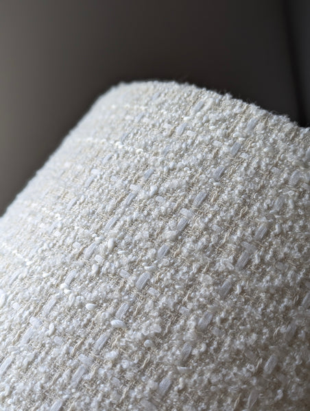 Close-up of textured fabric lamp shade in ivory boucle with a dark background