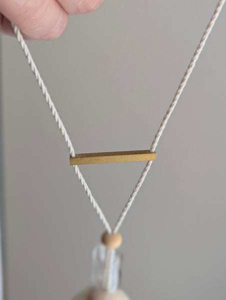 Decorative tassel with wooden and glass beads and a brass bar on a gray background