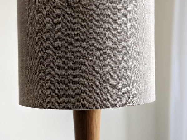 Close-up of the back seam of a herringbone fabric lamp shade on a walnut table lamp