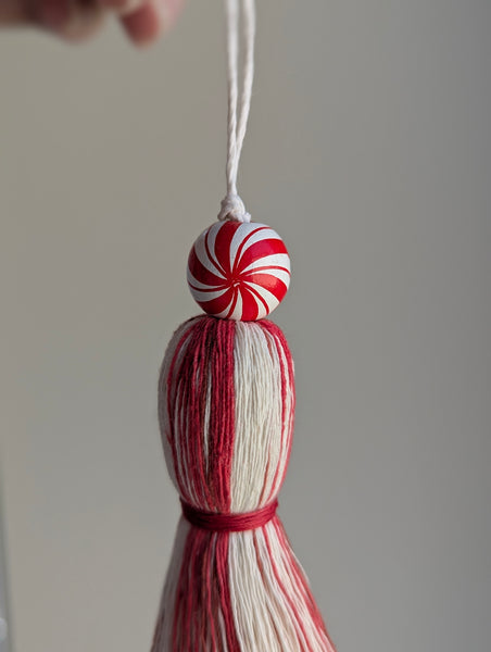 holiday tassel gift tag in red and white with a candy cane bead at the top