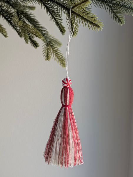 holiday tassel ornament in red and white with a candy cane bead at the top