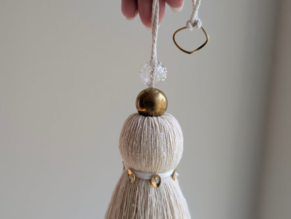 snowy white tassel in a natural cotton color with brass accents and a handblown glass bead