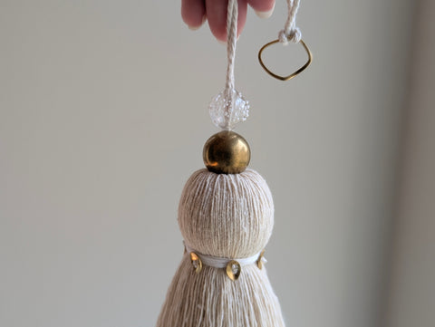 snowy white tassel in a natural cotton color with brass accents and a handblown glass bead