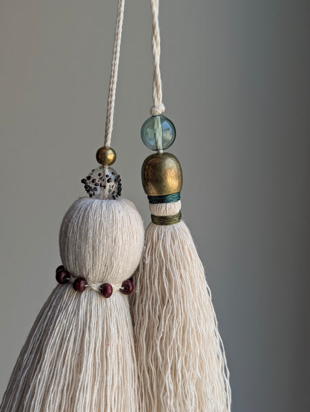 a small festive door tassel made of cotton with a green glass bead and brass accents