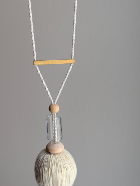 Decorative tassel with wooden and glass beads and a brass bar on a gray background