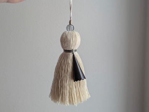 Decorative tassel with beige and black elements on a gray background