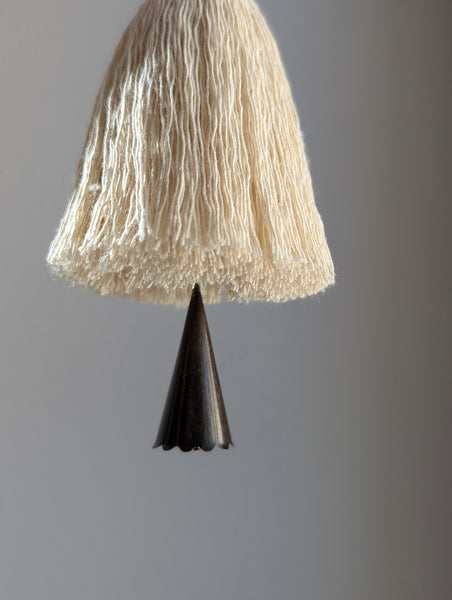dark brown bell on a tassel with a gray background