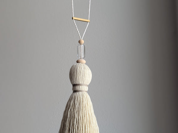 Decorative tassel with wooden and glass beads and a brass bar on a gray background
