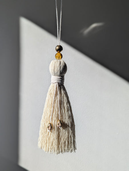 Decorative tassel with beads hanging against a light background
