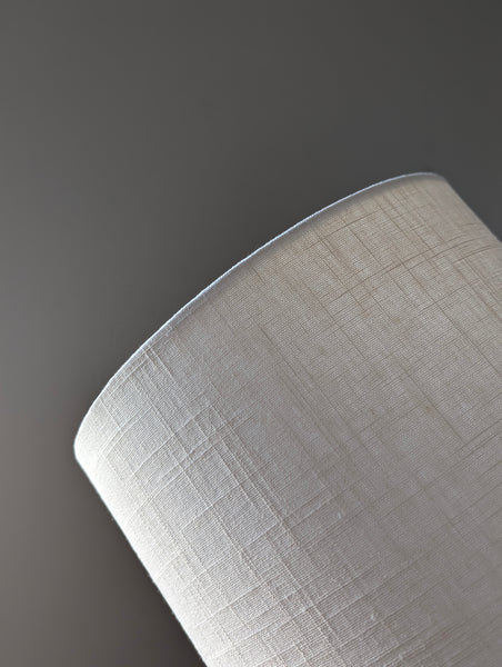 Close-up of a white linen textured lampshade on a dark background