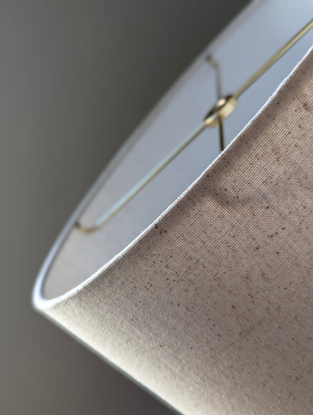 close up of the wrapped edge on an oval lamp shade in speckled oatmeal fabric