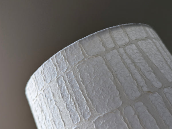 close up of the bottom edge of the paper lamp shade with a geometric pattern and a strong texture