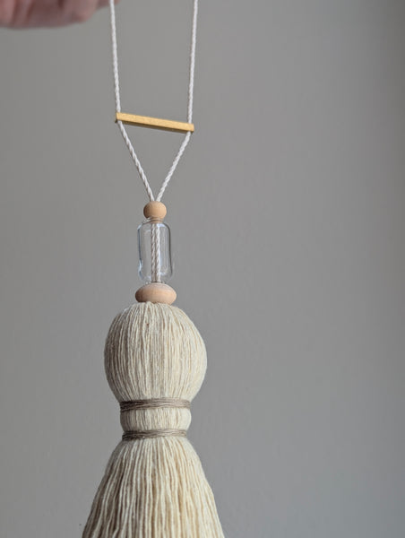 Decorative tassel with wooden and glass beads and a brass bar on a gray background
