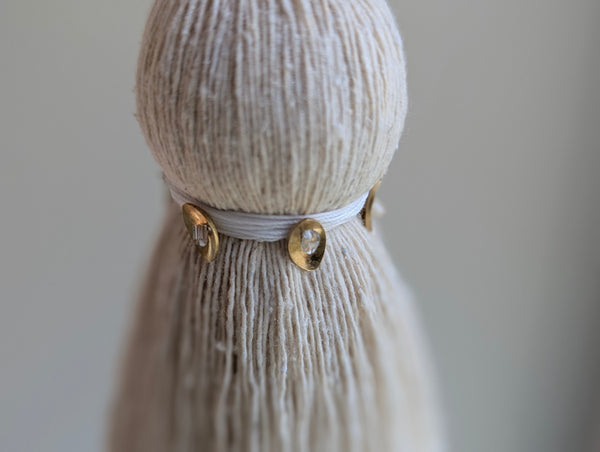 snowy white tassel in a natural cotton color with brass accents and a handblown glass bead