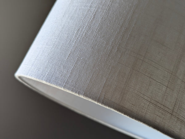 Close-up of a white linen textured lampshade on a dark background