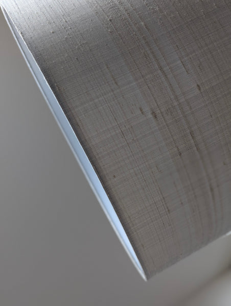 close up of a gray silk lamp shade with nubby gray texture
