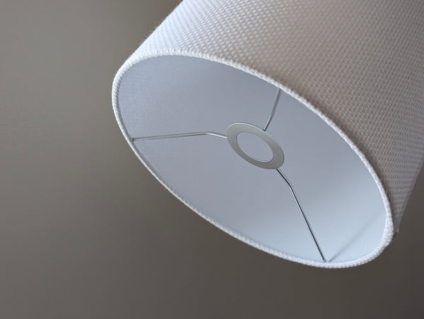 Close-up of a white textured lampshade in Bright White Crosshatch fabric against a soft gray background