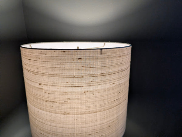 gray silk lamp shade lit in a dark green room
