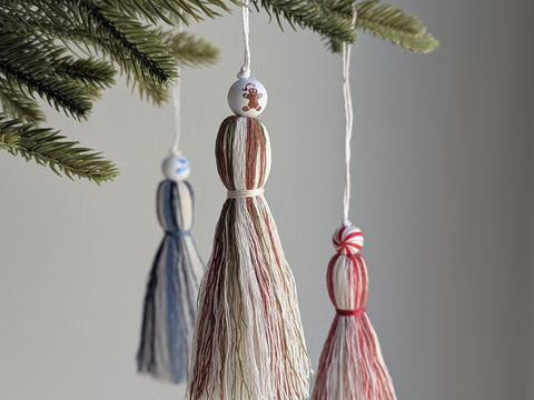 Three tassel ornaments hanging from a Christmas tree branch.