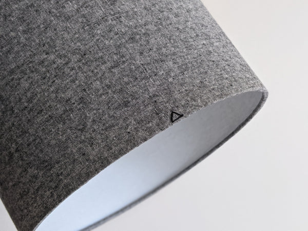 back and white woven fabric lampshade with a black triangle stitch detail on the back seam on a neutral background
