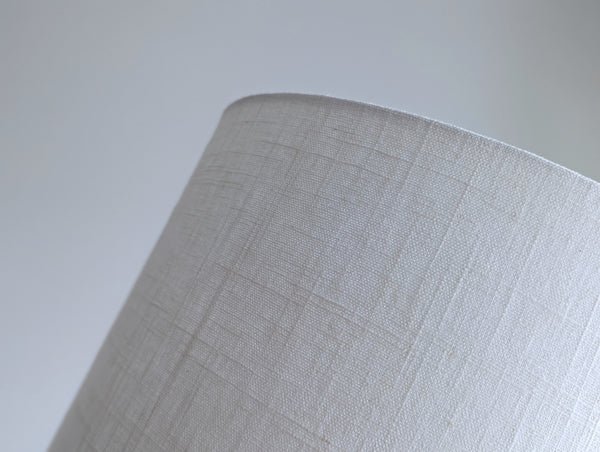 Close-up of a white linen textured lampshade against a neutral background