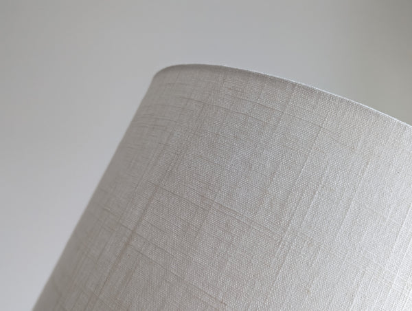 Close-up of a white linen textured lampshade on a neutral background