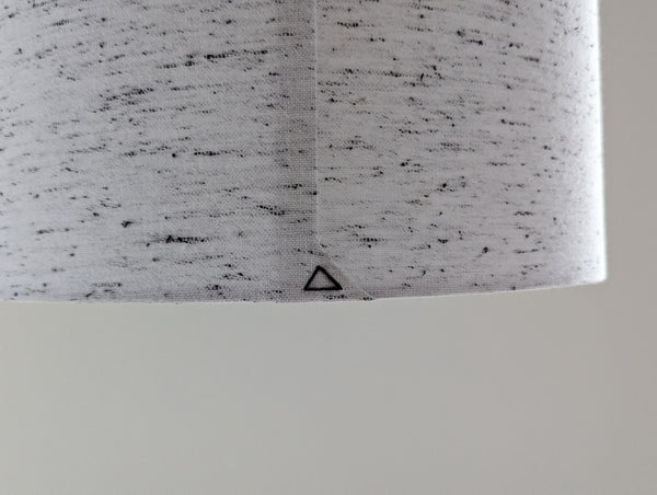 close up of the back seam black triangle stitch detail on a white lamp shade with small black flecks throughout the fabric