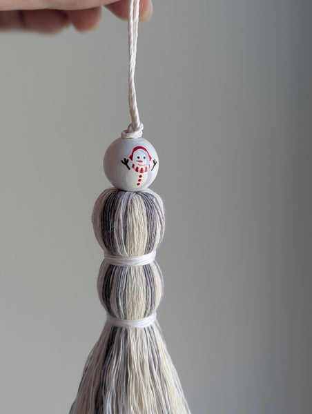 Decorative tassel ornament with a snowman design on a plain background