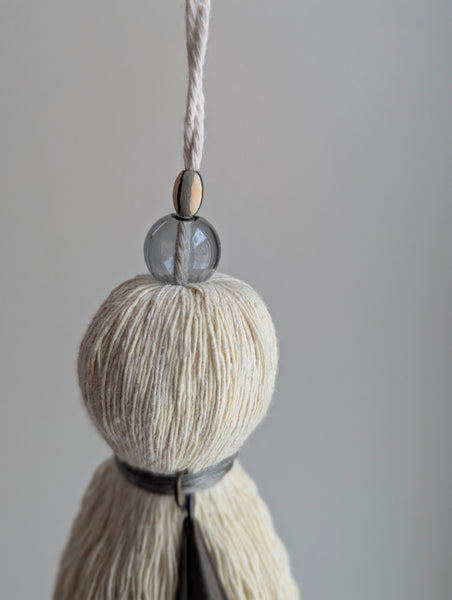Decorative tassel with a glass bead on a plain background