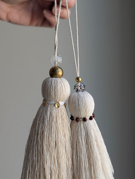 snowy white tassel in a natural cotton color with brass accents and a handblown glass bead