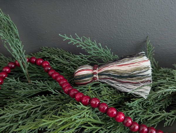 holiday tassel decor mixed into Christmas garland on a mantle