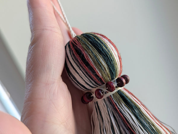red and green seasonal tassel door hanger with cranberry red wooden beads