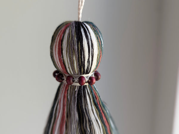 red and green seasonal tassel door hanger with cranberry red wooden beads