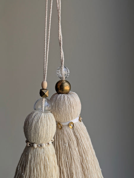 snowy white tassel in a natural cotton color with brass accents and a handblown glass bead