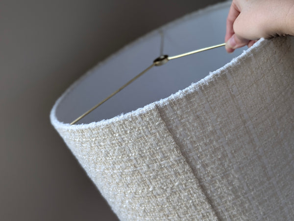 Close-up of a hand holding a textured boucle lamp shade showing the back seam