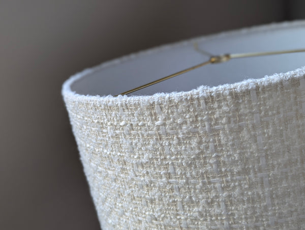 Close-up of a textured boucle lamp shade with brass spider washer hardware