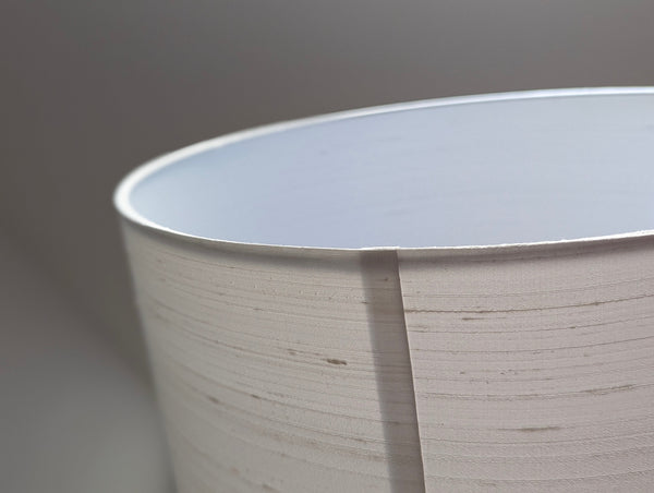 Close-up of a drum lampshade with a nubby silk texture and a white interior lining.