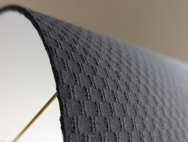 Close-up of a textured gray lamp shade with a blurred background