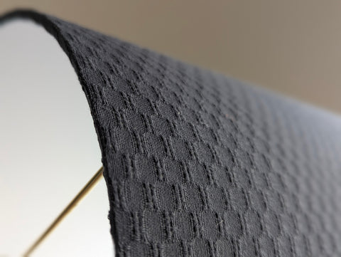 Close-up of a textured gray lamp shade with a blurred background